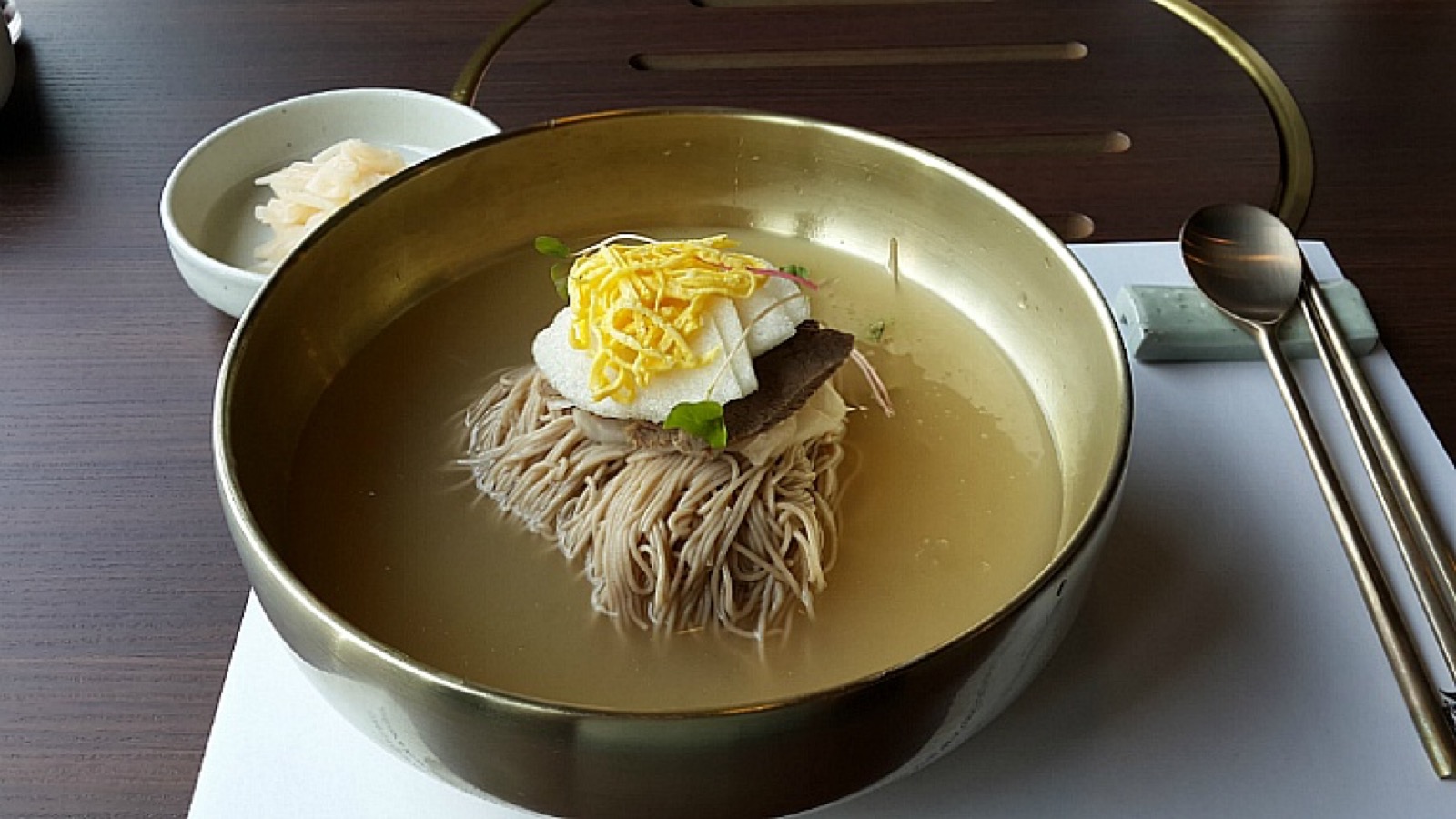 A bowl of Korean buckwheat noodles with broth and sliced toppings